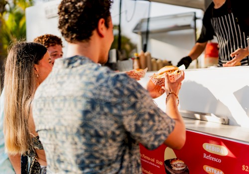 People are at a food truck, receiving food from a vendor.